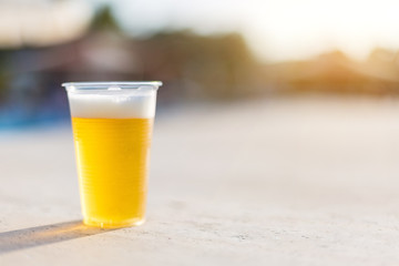 Plastic glass with cold beer. A small glass of plastic with beer in the sun.