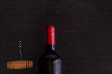 Red wine bottle with corkscrew of wooden table. Wine lovers concept background.