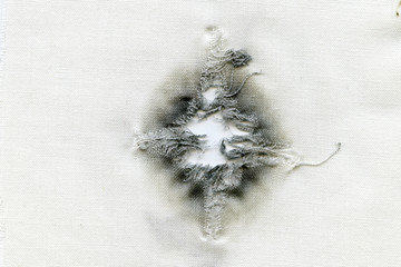 Bullet hole on a white cloth when shot at point-blank range from a 45-gauge weapon, abstract...