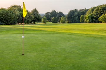 Obraz premium Putting Green mit gelber Fahne in der Abendsonne