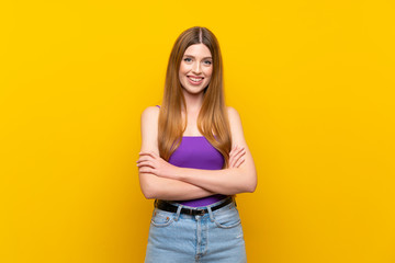 Fototapeta premium Young woman over isolated yellow background keeping the arms crossed in frontal position