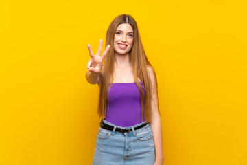 Young woman over isolated yellow background happy and counting three with fingers