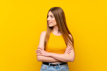 Young woman over isolated yellow background looking to the side