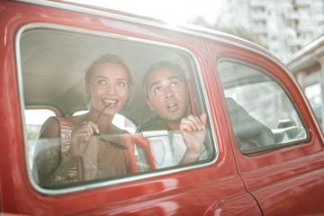 Amazed tourists looking out of the car window.