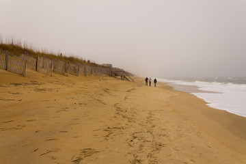 Unidentified People Walking Atlantic Coast Beach on Foggy Day.