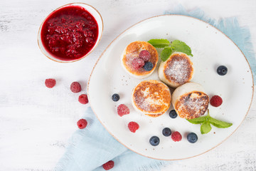 Fried cottage cheese pancakes decorated with fresh berries and mint. Vertical orientation. Top view