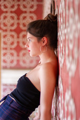 Naklejka premium Portrait of young pretty woman leaning on pink designed wall with white ornament and looking away