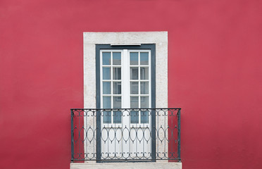 Haus Fassade weinrot gestrichen, Tür mit Lattenfenster und grau weißer Umrahmung, kleiner Balkon