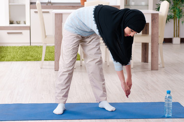 Young woman in hijab doing exercises at home
