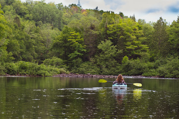 woman kayaking on quiet river in forest