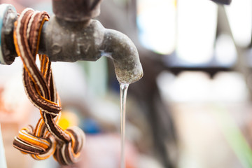 Water flowing from the old faucet. Selective focus and blurred background.