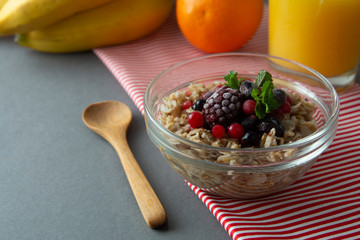 Healthy breakfast in a bowl with oatmeals, frozen berries, fresh strawberries, mint. Oat porridge with fruits.