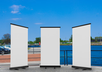 3D rendering of blank vertical rollup (empty billboard advertisement) with city background. Empty mockup template