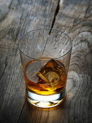 close up view of  glass with ice and whiskey on wooden background