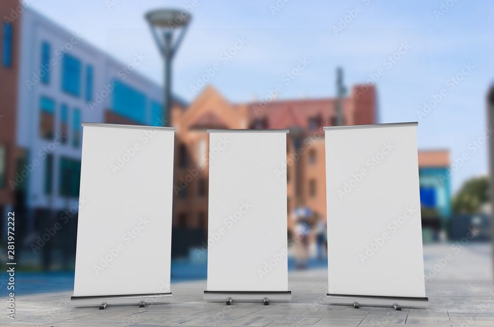 Wall mural 3d rendering of blank vertical rollup (empty billboard advertisement) with city background. empty mo