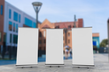 3D rendering of blank vertical rollup (empty billboard advertisement) with city background. Empty mockup template