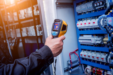 Technician use infrared thermal imaging camera to check temperature at fuse-box © romaset