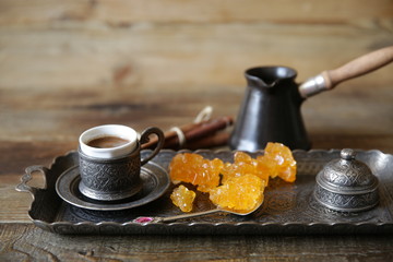 Close-up turkish coffee in cups with vintage pattern with cezve and sweet sugar caramel on a wooden rustic table with copy space for text and image. Still life.
