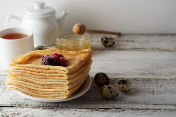 Stack of thin pancakes decorated with strawberries and blueberries. Russian holiday Maslenitsa. Healthy breakfast. Copy space.