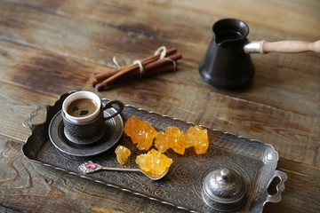 Naklejka premium turkish coffee in cups with vintage pattern with cezve and sweet sugar caramel on a wooden rustic table. Still life. Top view. 