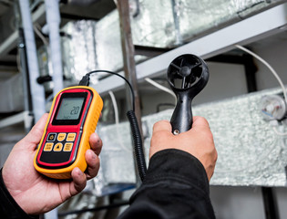 Technician use hand-held anemometer measuring air flowing measurement, wind speed and pressure.