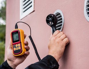 Technician use hand-held anemometer measuring air flowing measurement, wind speed and pressure.