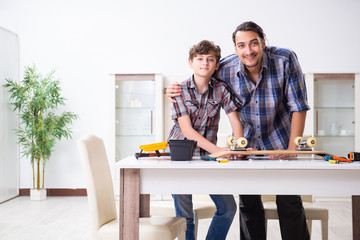 Young father repairing skateboard with his son at home
