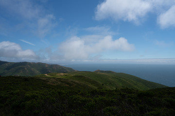 Green horizon with rolling blue hills and dirt paths and ocean