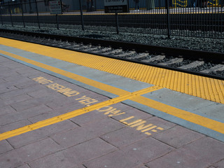 Wait behind yellow line warning on ground on train platform