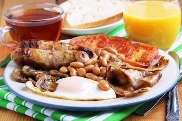 Classic English breakfast served: eggs, bacon, beans, juice and tea	