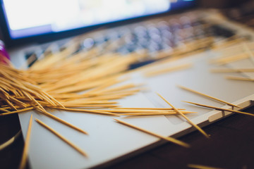 many wooden toothpicks on the brown table background a laptop.
