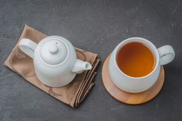 Tea. Cup of tea and teapot. White ware on a black stone table. Top view