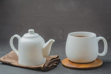 Tea. Cup of tea and teapot. White ware on a black stone table. Selective focus