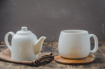 Tea. Cup of tea and teapot. White ware on a wooden table. Selective focus