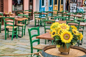 leeres straßencafe mit sonnenblumen in burano, italien