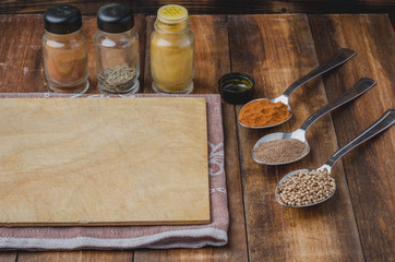 Various spices, cutting board over wooden table background.