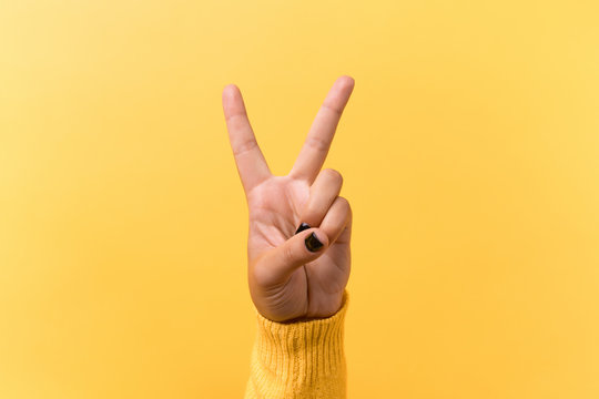 Hand gesture V sign for victory or peace sign over yellow background