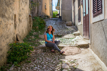 Fototapeta premium Young woman on the stairs of a old Croatian city.