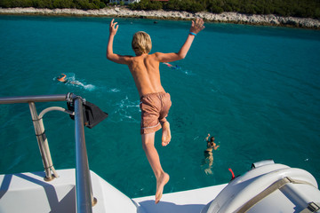 Young boy jumping off a boat, enjoying the freedom of his summer holiday