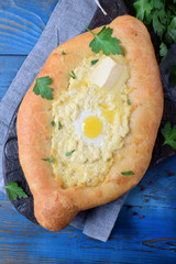 Adjarian khachapuri of yeast dough with sulguni cheese, quail egg and butter. Caucasian cuisine meal