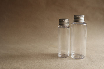 Model image of a clear glass bottle with a metal cover on a brown background,mockup