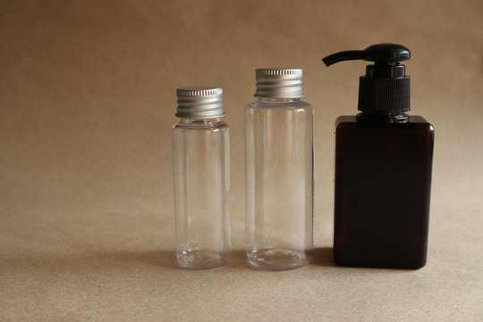  Model image of a clear glass jar with metal lid and a brown bottle with a squeeze cap on a brown background,mockup