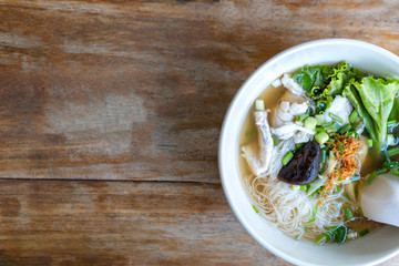 Soup with thin noodle, pock, pock stick, mushroom, vegetable in white bowl on wood table. with copy space for text or design