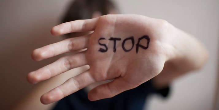 Teen boy protects himself with a palm with the word "stop"