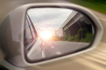 Abstract Blurred image. The view of the side of the mirror white car. with the car coming from behind with the bright orange light and the side view at the speed.