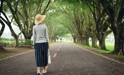 woman take a walk on the way under the trees