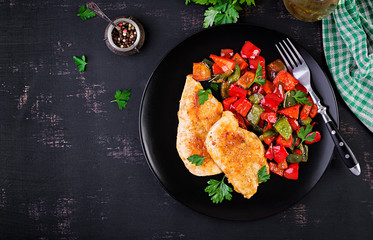 Grilled chicken fillets and sweet pepper on black plate. Top view, copy space
