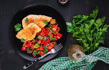 Grilled chicken fillets and sweet pepper on black plate. Top view, copy space