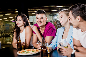 Cheerful friends in the pub. Drinking beer, wine and whisky, talking, having fun.