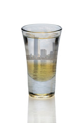Cocktail with three layers of alcohol in shot glass with landscape view of the city inside isolated on white